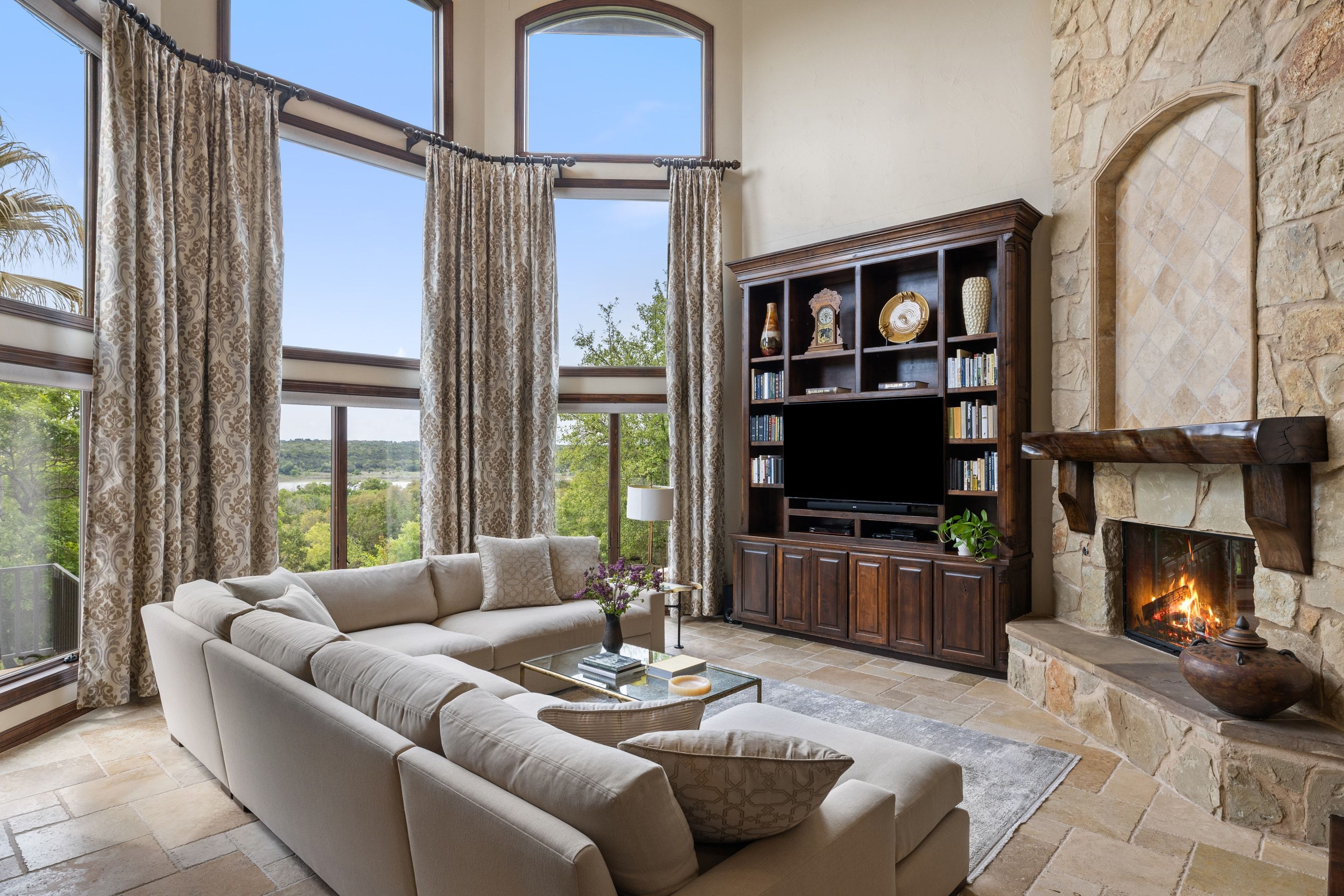 Main living room at Lakehaven with a stone fireplace, soaring windows, and panoramic views