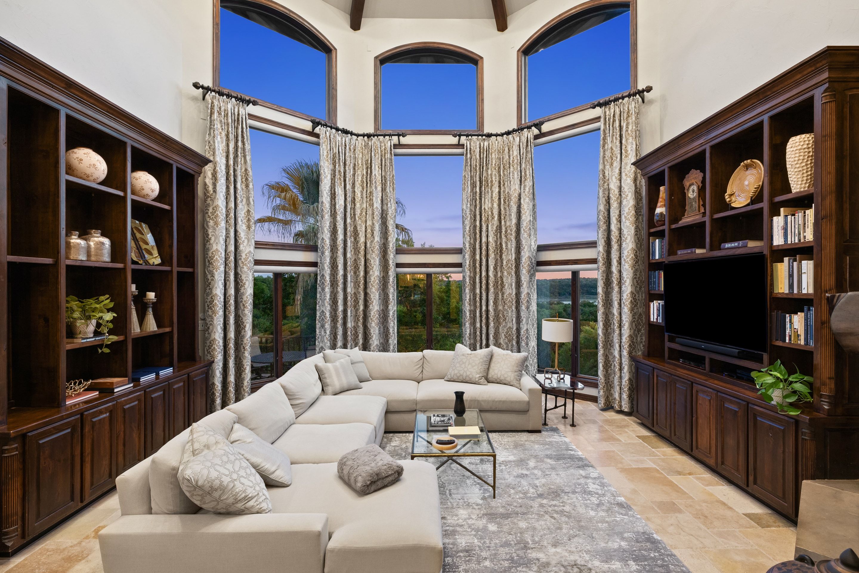 Main living room at Lakehaven at twilight with floor-to-ceiling windows and a stone fireplace