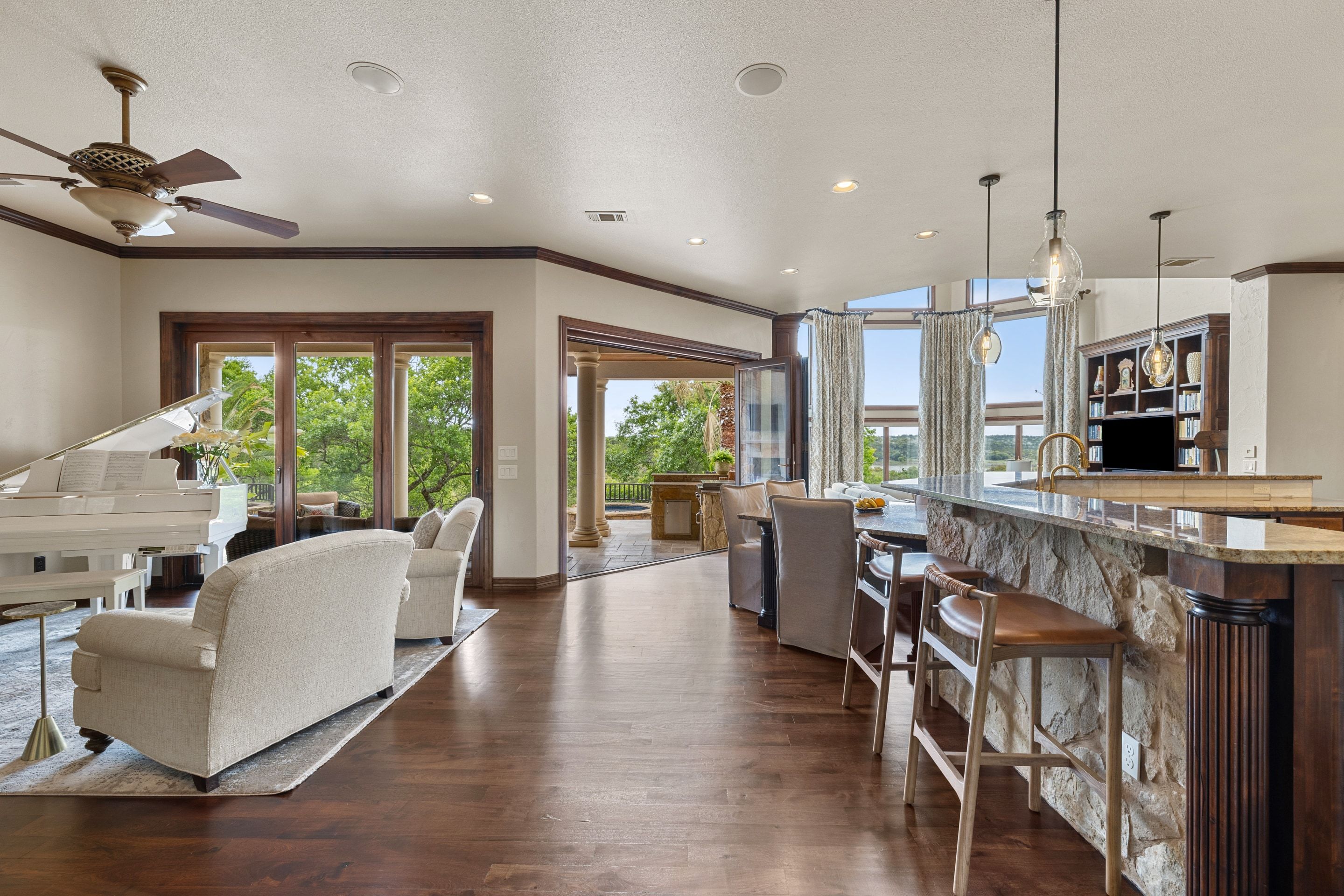 Open kitchen and living sequence at Lakehaven with piano area and covered patio beyond