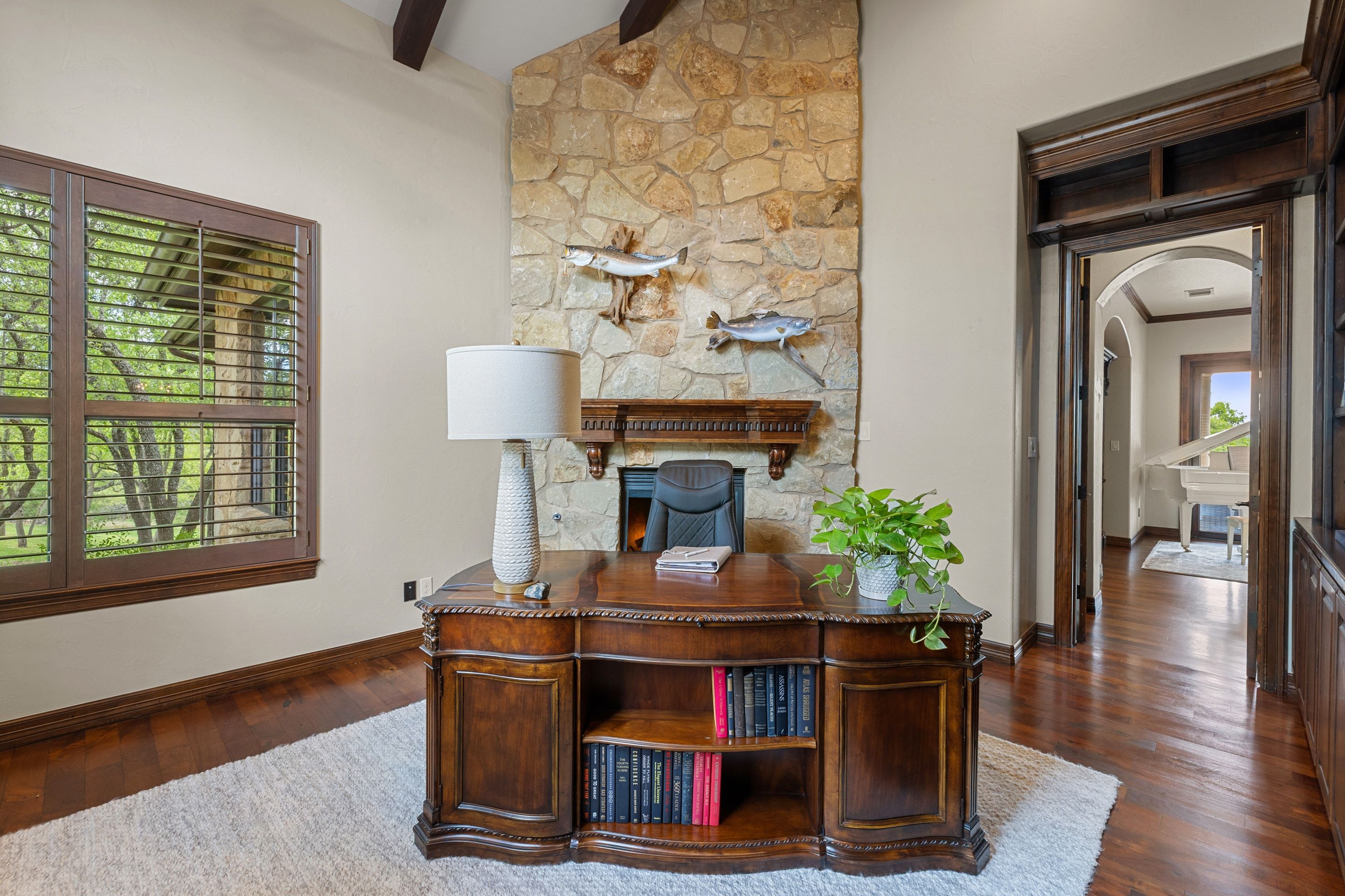 Study at Lakehaven with a stone fireplace, built-in desk, and custom shelving