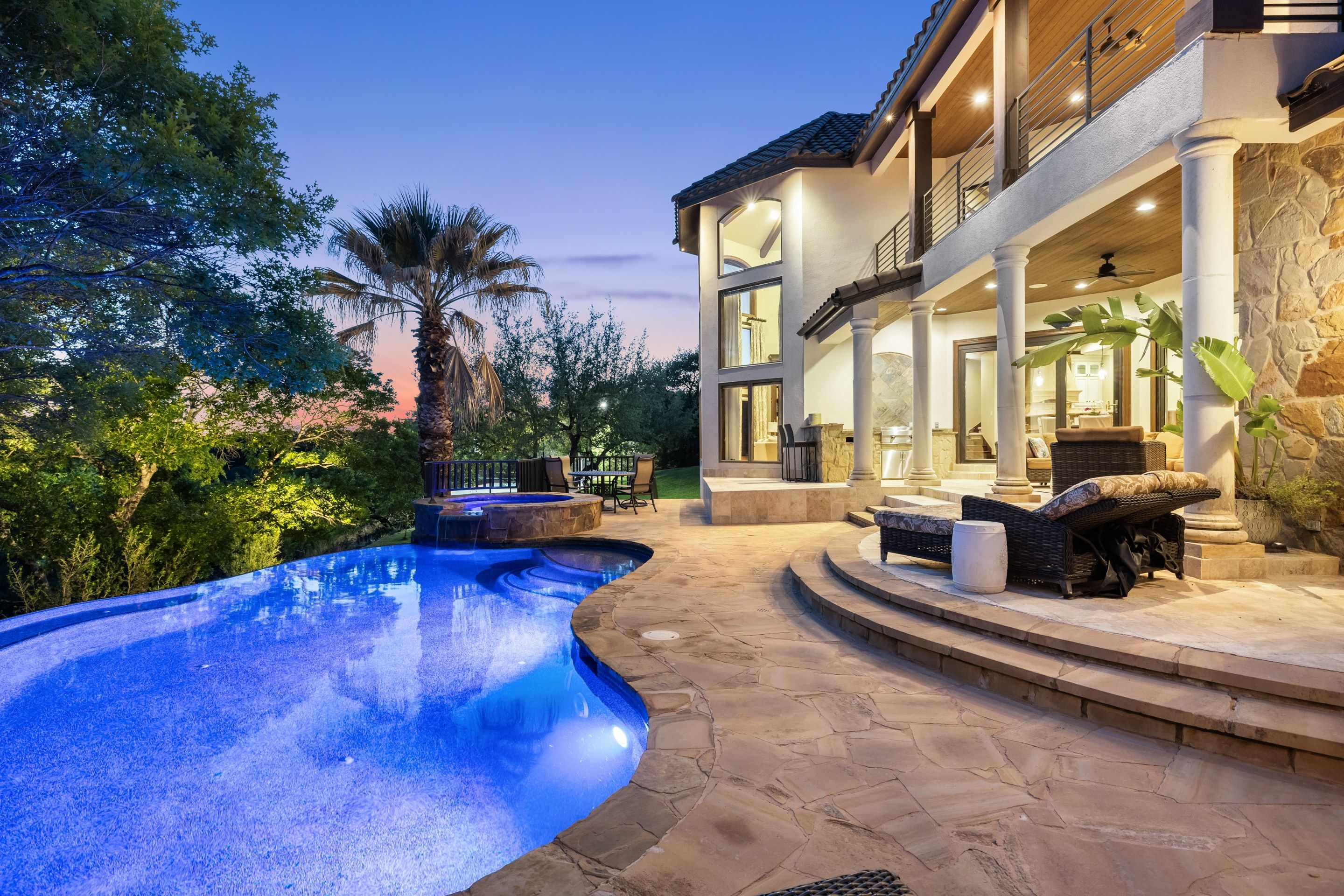 Lakehaven pool terrace at twilight with the spa, covered patio, and outdoor seating