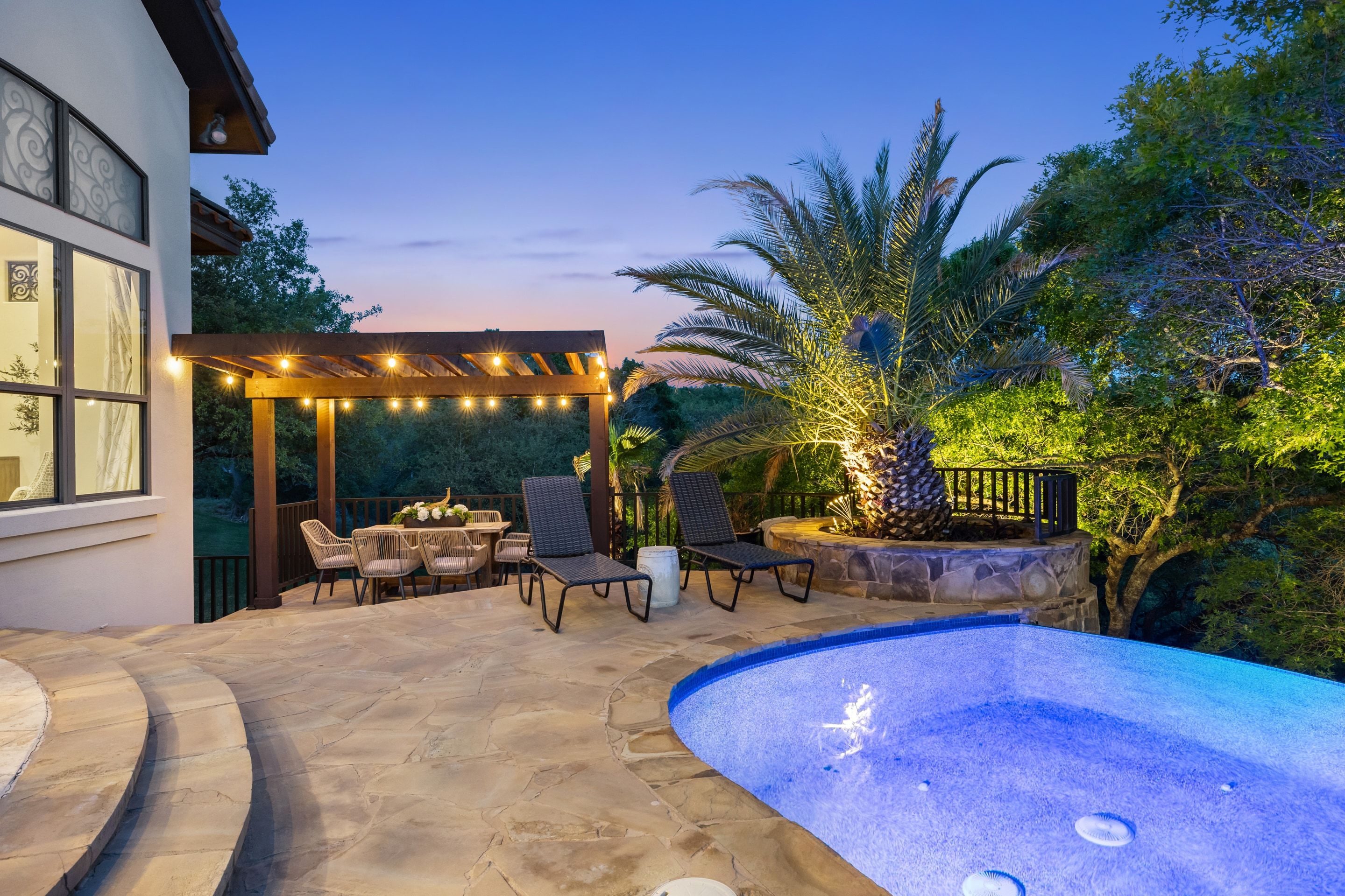 Pool terrace at Lakehaven with the pergola, lounge seating, and illuminated palms at dusk