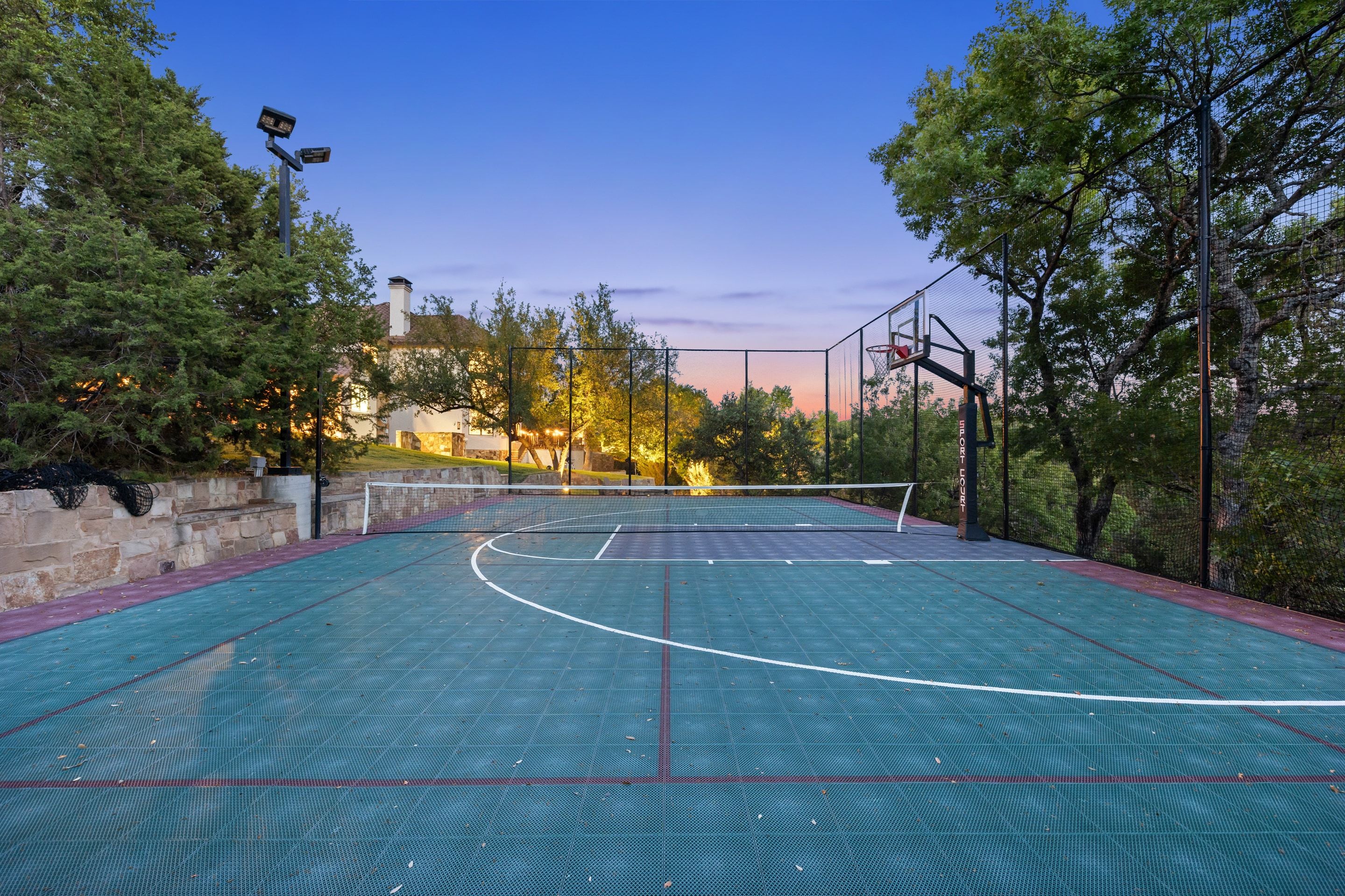 Fenced and lighted sport court at Lakehaven at twilight