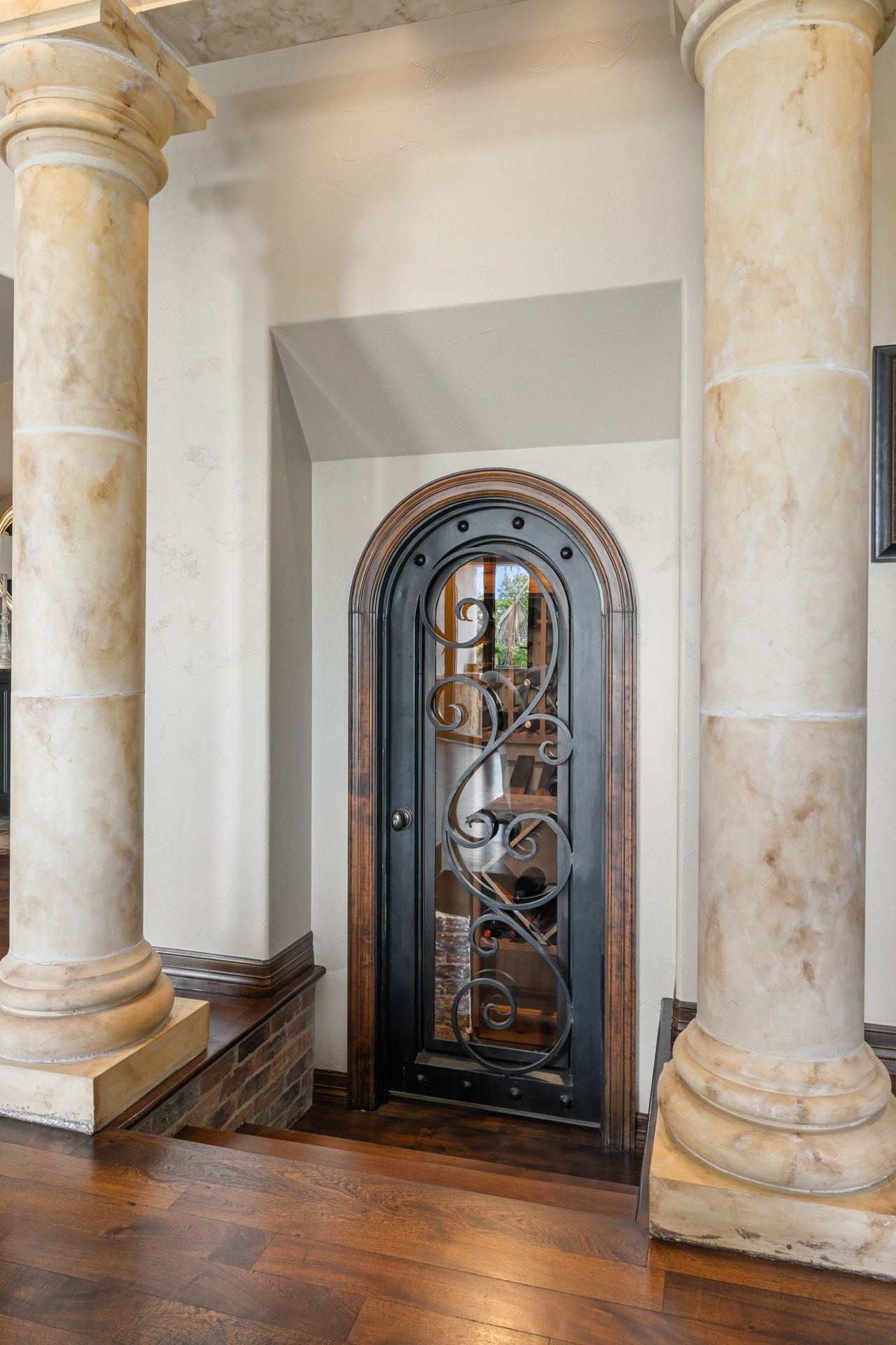 Arched iron wine room door at Lakehaven framed by column details