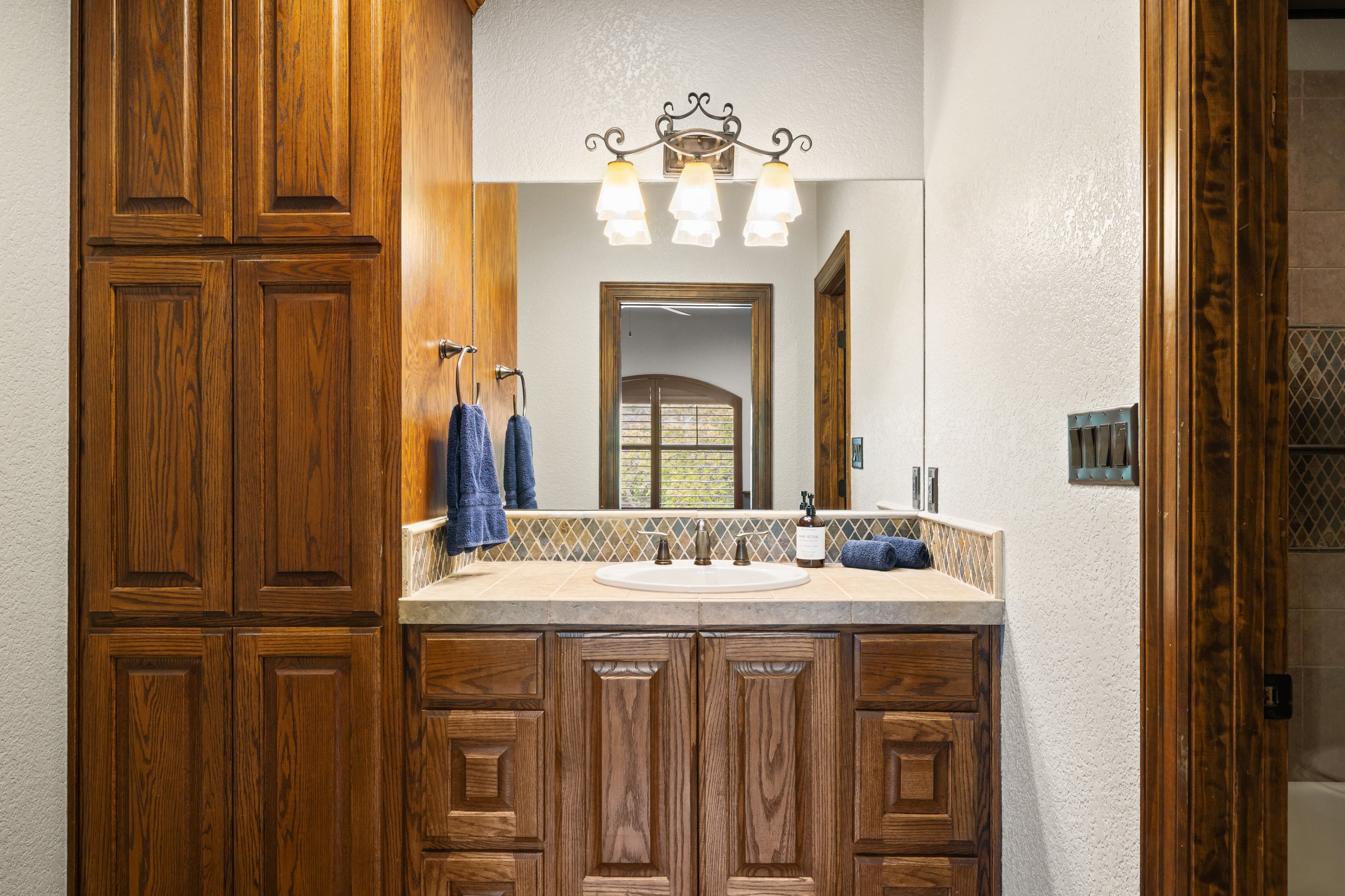 Secondary bath vanity at Lakehaven with custom wood cabinetry and stone tile