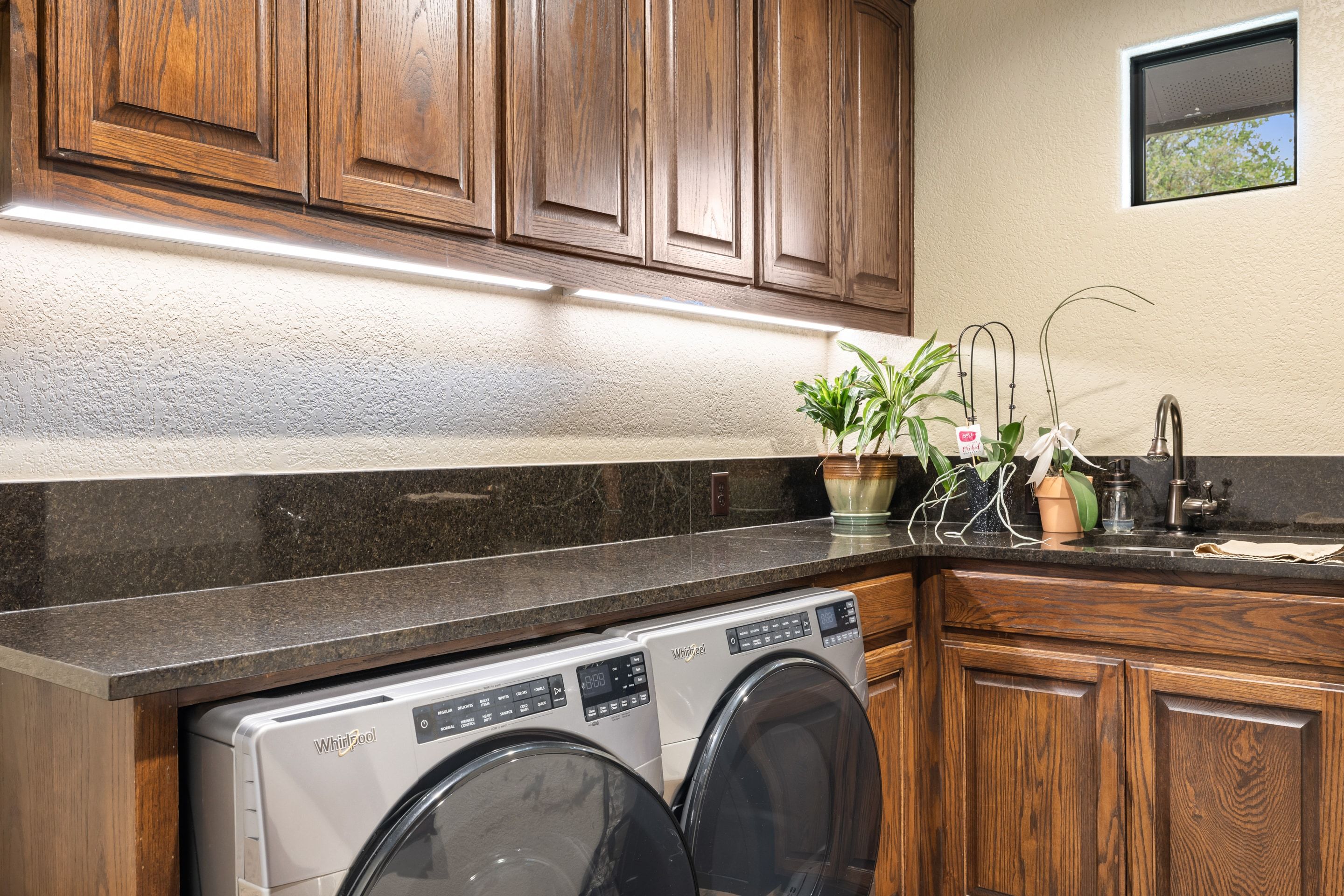 Laundry room at Lakehaven with stone counters, sink, and custom cabinetry